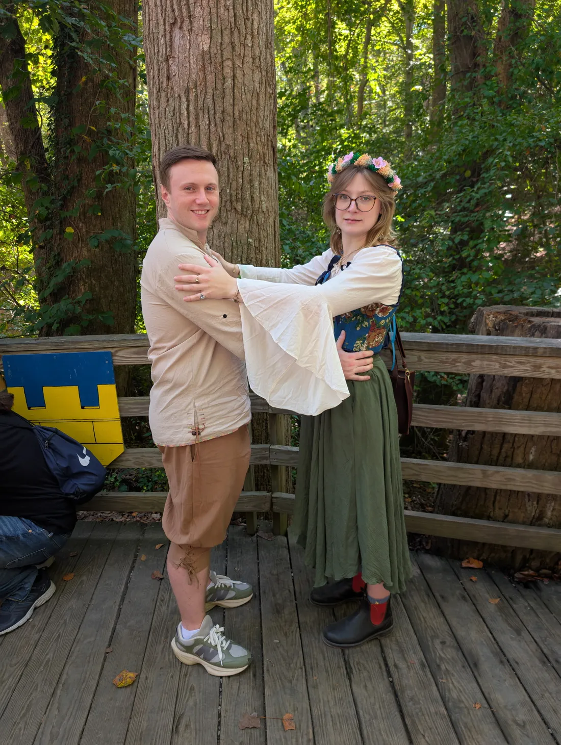 Cat and Zach in Renaissance-festival outfits on a wooden bridge in the woods.