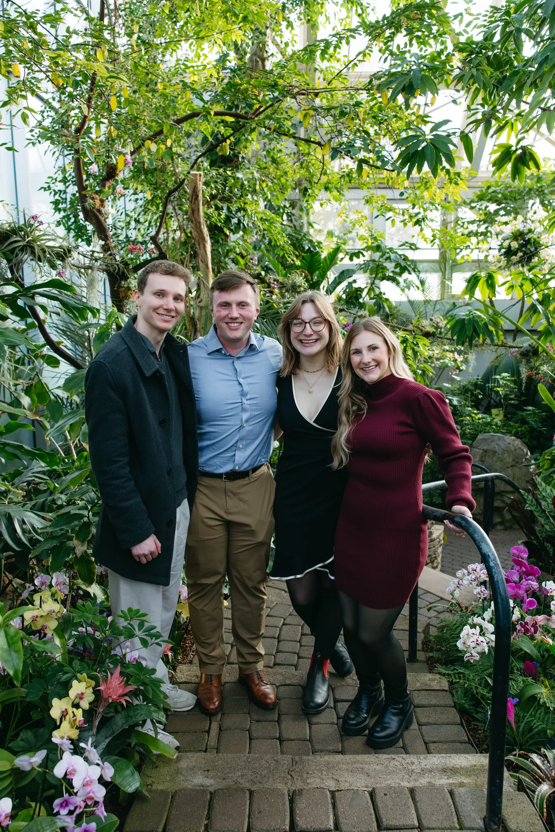 Four friends on a garden path at the Franklin Park Conservatory, among orchids and tropical plants.